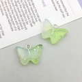 Macro detail of two light green translucent resin butterfly pendants with glitter and metal rings - Green Blue Gradient Resin Butterfly (17051)