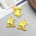 Macro detail of three gold graduation cap and scroll charms for DIY jewelry making - Gold