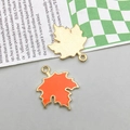 Detail von Ahornblatt-Anhängern mit orangefarbener Emaille und goldener Rückseite - Orange