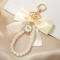 Macro shot of satin bow and luminous pearls with a crystal-encrusted heart charm keychain - Cream Bow (ZJ15863)