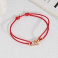 Detailed view of woven red cord bracelet with metal U-shaped buckle and adjustable knot - Red