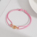 Detail of pink woven bracelet featuring a gold U-link horseshoe clasp and gold metal beads - Pink