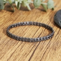 Detailopname van een dubbele rij tijgeroog en hematiet kralenarmband op hout - Dubbele Rij Hematiet Geslepen Kralen(ZJ16243)