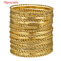 Set van 19 gouden armbanden met gedraaide ontwerpen en bloemtexturen op witte achtergrond - Gouden Reliëf Bloemen Stapelbare Stijl (ZJ10588)