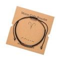 Close-up of Aries Morse code bracelet with black cord, wood beads and display card - Aries