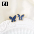 Elegantes pendientes de mariposa dorados con esmalte azul sobre plato de porcelana blanca - Estilo Azul Oscuro (B1)