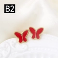 Primer plano detallado de pendientes de mariposa roja en una bandeja de cerámica - Estilo Rojo Brillante (B2)