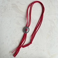 Detail van rode imitatie suède bolo tie met zilveren gravure en modieuze franjes - Rood