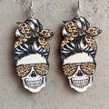 Detail of wooden skull earrings with leopard print bow and American tie-dye baseball motif - Wood Leopard Messy Bun Skull