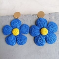 Detail of blue raffia flower earrings with yellow woven center on stone surface - Dark Blue