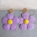 Detail of bohemian raffia flower earrings in purple and yellow on a stone surface - Purple