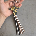 Detail of western cowboy cow head keychain with sunflower print and fringe tassels in hand - Bull Head Sunflower Style