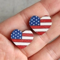 Wooden heart-shaped earrings featuring US flag patterns held in hand for scale - Heart Style