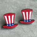 Macro shot of Uncle Sam hat earrings with American flag patterns on stone surface - Fedora Style