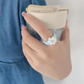 Light blue clay ring featuring a white floral ornament worn by a model with a coffee cup - Blue Base White Flower Style(ZJ8109)
