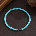 Blauwe turquoise kralenarmband met evil eye bedel en zilveren kralen op leer achtergrond - Turkoois