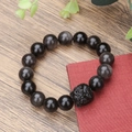 Detailed close-up of obsidian beaded bracelet featuring a black Pixiu charm on wooden surface - Black Pixiu Style (12mm ZJ11258)