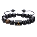 Macro-opname van 10mm onyx armband met tijgeroog en gouden letter A bedel aan koord - Letter A