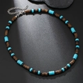 Bohemian ketting met turquoise en houten kralen op een donkere getextureerde mat - Turkoois Blauwe Cilindrische Kraal Etnische Stijl (ZJ12765)