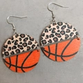 Macro shot of circular leopard print and orange basketball textured leather earrings - Basketball Style