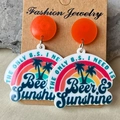 Gros plan de boucles d'oreilles en acrylique Beer & Sunshine avec des palmiers - Style Texte Arc-en-ciel et Beer Sunshine