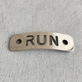 Detailaufnahme von silbernem Schnürsenkel-Charm aus Metall mit RUN-Ausschnitt und Löchern - RUN Stil (1)