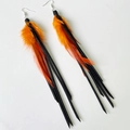 Macro detail of Bohemian long earrings with orange feathers and black suede tassels - Bright Orange (Black Cord)