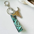 Detail of Western bull skull keychain with rhinestone inlay and floral embossed leather strap - Brown Velvet Texture Bull Head