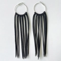 Macro detail of Bohemian oversized silver hoops with long black suede fringe tassels - Black
