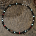 Ethno-Perlenkette mit Lavasteinen und goldener Vintage-Perle auf dunklem Holzgrund - Schwarze Lavagestein Matte Perlen Rot Grüne Farbige Perlenkette (ZJ14180)