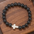 Herenarmband van zwarte lavasteen kralen met een wit kruisje op houten achtergrond - Lavasteen met Wit Kruis (ZJ14083)