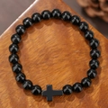 Obsidiaan kralenarmband met kruisbedeltje op een rustieke houten ondergrond - Gepolijste Obsidiaan Stijl (ZJ14084)