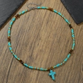 Boho-Perlenkette mit Türkis-Kreuz-Anhänger auf rustikalem Hintergrund aus Holz und Stein - Kreuzanhänger Tigerauge Türkis (ZJ15011)