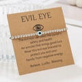 Close-up of silver CCB beaded Evil Eye bracelet on kraft paper gift display card - Black Eye (ZJ15639)