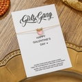 Nahaufnahme des goldenen Herzarmbands auf einer weißen Galentine's Day Geschenkkarte - Rosa (ZJ15651)