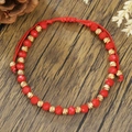 Detalle de pulsera de la amistad con cuentas rojas y toques dorados sobre madera - Estilo de Cuentas de Cuerda Roja (ZJ15671)