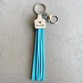 Dettaglio portachiavi con nappa blu e ciondolo in metallo inciso Cowgirl argentato - Stile Testa di Mucca (1)