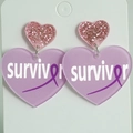 Detail of pink glitter and purple acrylic heart earrings with survivor text and ribbon - Lavender