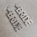 Makro-Detail der silbernen Glitzer BRIDE Buchstaben-Ohrringe für Brautparty-Accessoires - Silber Glitzer Braut
