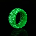 Macro view of luminous resin ring showing green glowing fibers and wood grain texture - Green