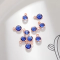 Macro shot of 6mm deep blue faceted crystal charms in rose gold plated frames for DIY jewelry - 6mm / Rose Gold - Blue (September)