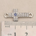 Detail eines silbernen Kreuzanhängers mit bösem Blick und Strasssteinen neben dem Lineal - Kreuz Blau Böser Blick Stil (P2568)