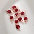 Macro-opname van 6mm rode glazen geboortesteen bedeltjes met een roségouden metalen rand - 6mm / Rozegoud Januari (P2460)