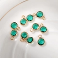 Close-up of circular emerald green faceted crystal charms with gold-plated metal frames - 6mm / Gold-Green (May)