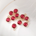 Macro shot of 10 red faceted 6mm birthstone charms with gold plating in a white ceramic dish - 6mm / Gold - Red (October)