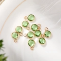 Macro shot of 6mm light green faceted crystal birthstone charms with gold plated frames - 6mm / Gold - Green (August)