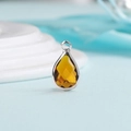 Macro shot of amber yellow teardrop crystal pendant with silver metal base and loop - Silver Border September (P2301)