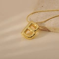 Macro shot of gold bubble letter B pendant necklace with elegant snake chain detail - Letter B Style (24WN028)