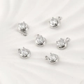 Dettaglio macro di sei ciondoli tondi argentati con zirconi chiari in castone a 4 griffe - Stile Rotondo / 10.7*8.2mm / Argento