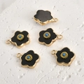 Detailed macro view of five black enamel flower pendants with gold plating and blue beads - Black Stone